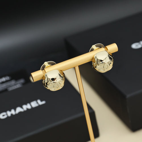 Gold-tone button stud earrings with Chanel-style logo shown on jewelry display
