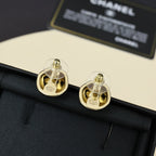 Gold-tone button stud earrings with Chanel-style logo on dark fabric pouch