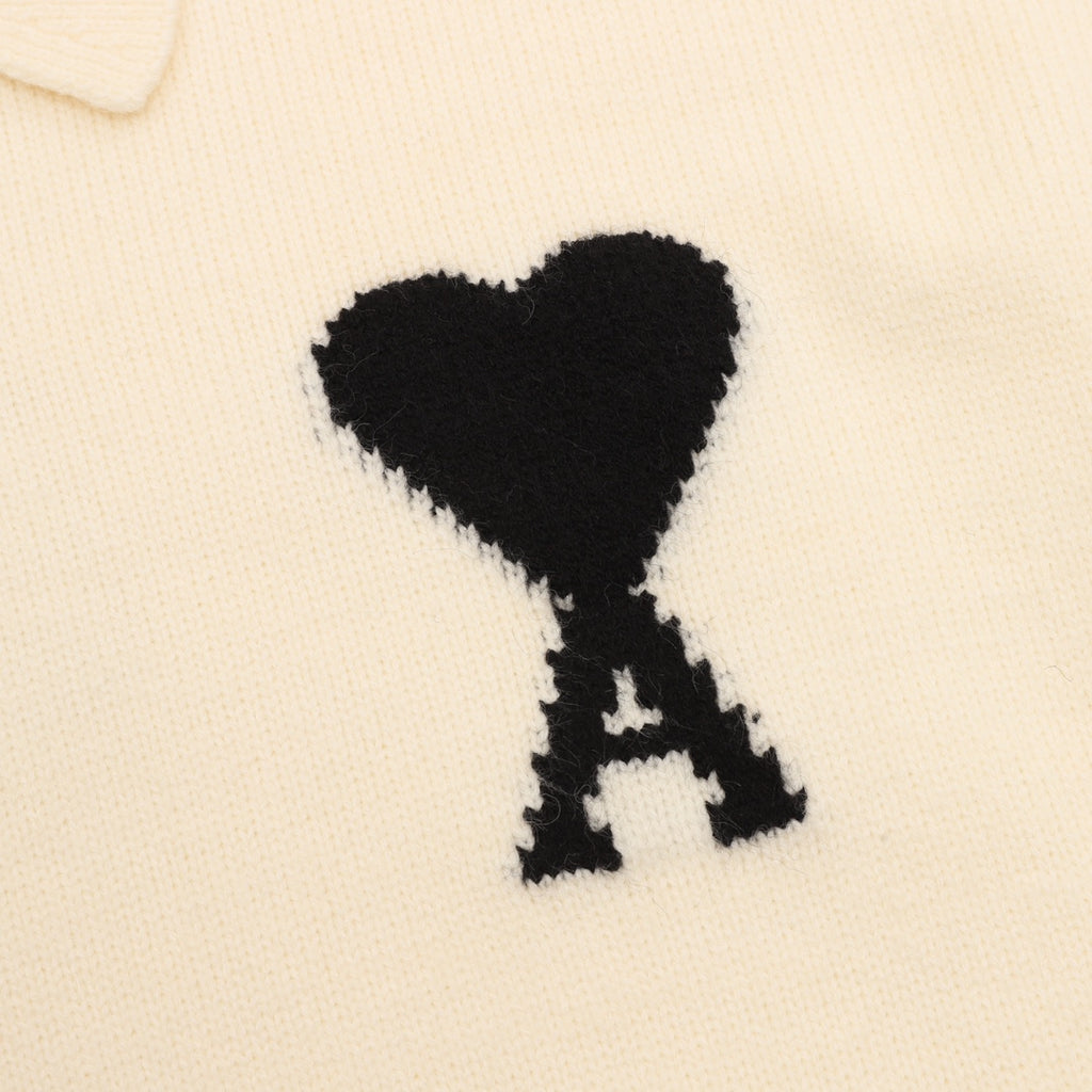 Amiri knit sweater detail: black heart-shaped 'A' applique on cream knit