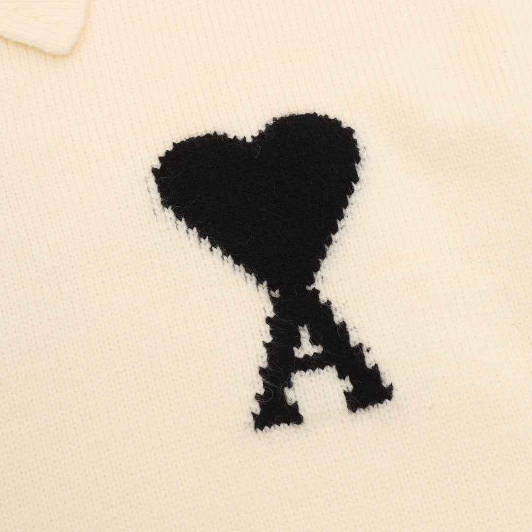 Amiri knit sweater detail: black heart-shaped 'A' applique on cream knit