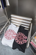 Pair of T-shirts on hangers: white and black with red crest logos