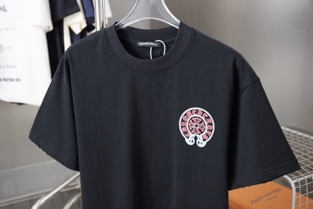 Dark navy crewneck T-shirt with small chest embroidered-style circular pink logo.