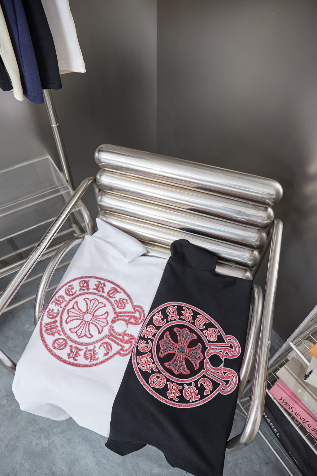 Pair of short-sleeve T-shirts on a chair: white and dark navy, each with pink circular logo.