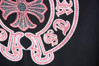 Close-up of circular pink emblem and surrounding lettering on dark T-shirt fabric.
