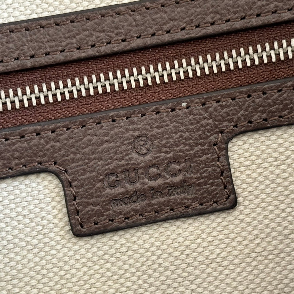 Brown leather logo patch with GG embossing on light canvas zipper edge