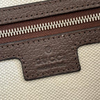 Brown leather logo patch with GG embossing on light canvas zipper edge