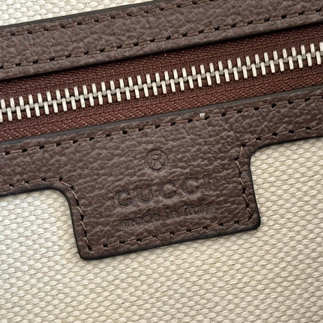 Brown leather logo patch with GG embossing on light canvas zipper edge