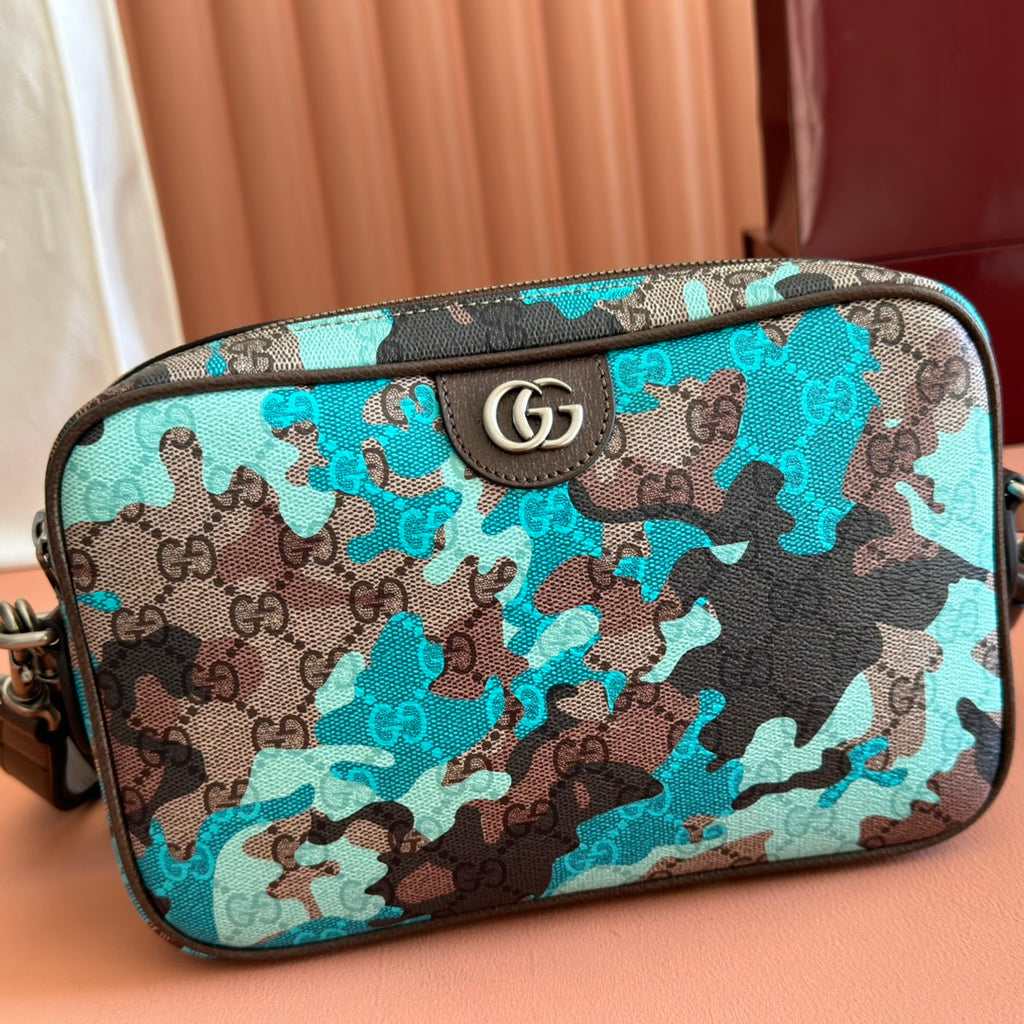 Teal camo GG zip pouch with brown leather trim and silver logo emblem