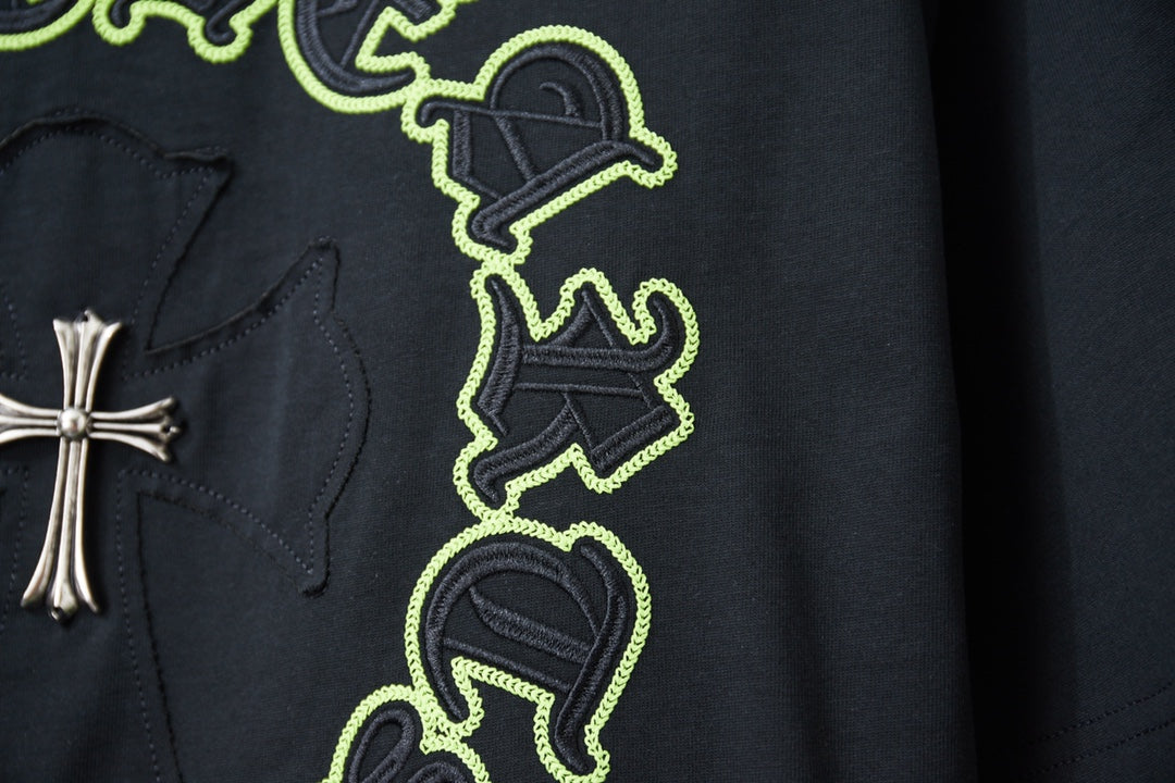 Dark T-shirt with neon green graphic patch and small cross detail