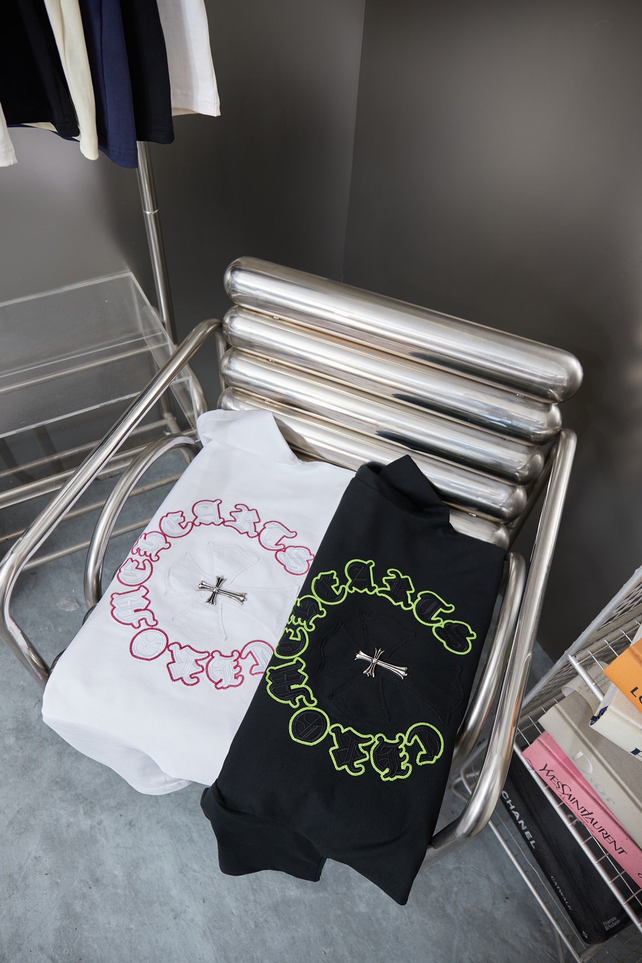 Folded white and dark T-shirts with neon green and pink circular cross graphics