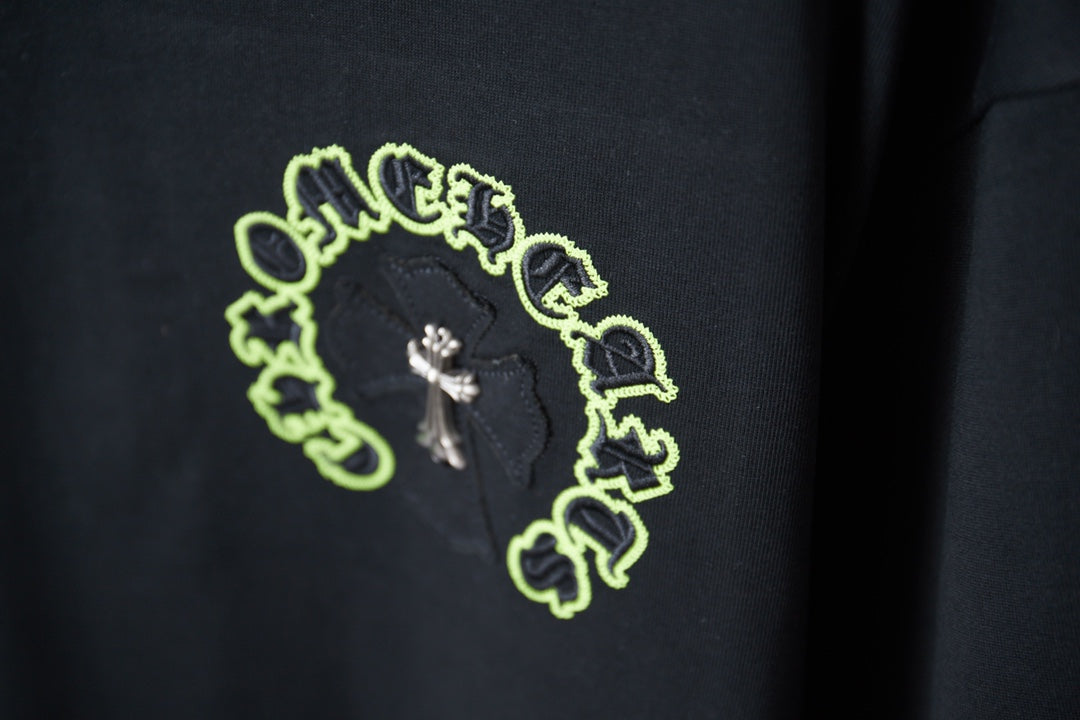 Neon green circular crest graphic with small cross on dark T-shirt