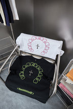 Folded white and black T-shirts with neon green and pink circular cross graphics