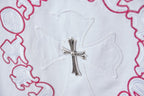 White T-shirt close-up of silver cross embroidery with red ring stitching