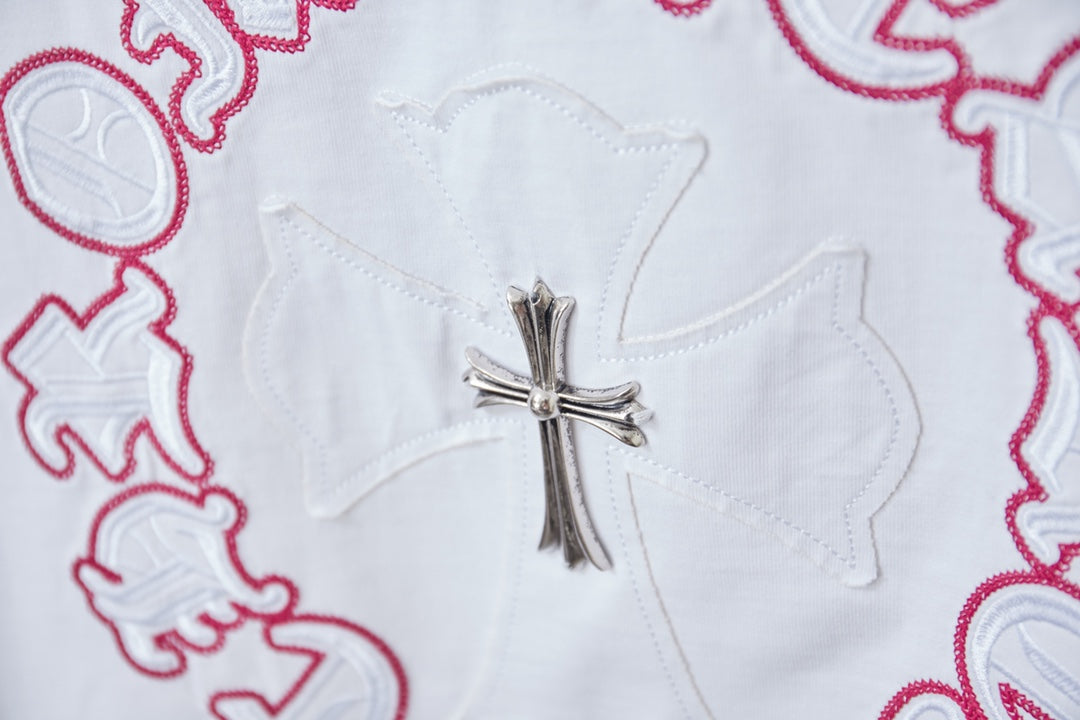 White T-shirt close-up of silver cross embroidery with red ring stitching