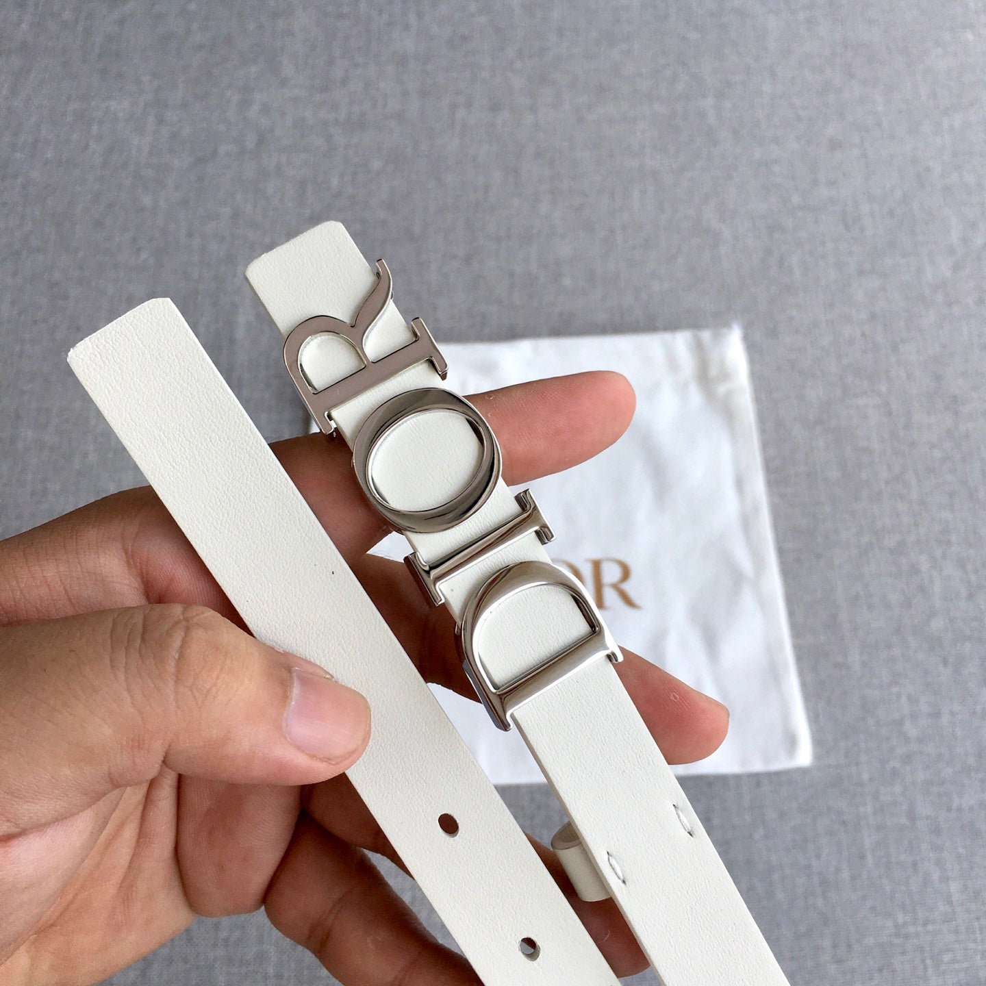 Dior belt close-up of light ivory strap end with holes and silver-tone buckle
