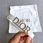 Dior belt held up to show light ivory strap and silver-tone buckle