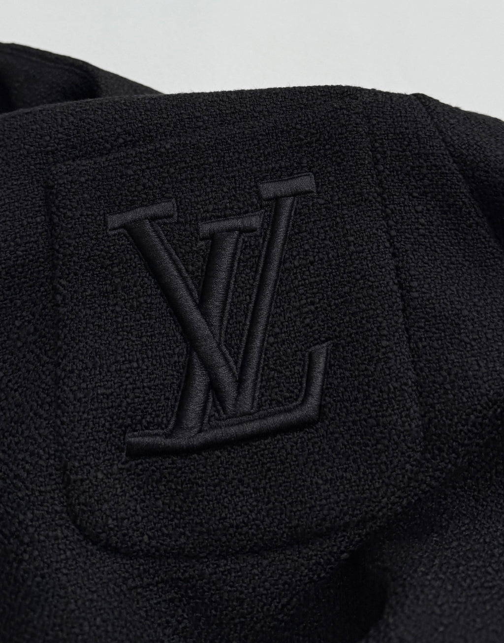 Black Louis Vuitton jacket chest detail with embossed LV monogram