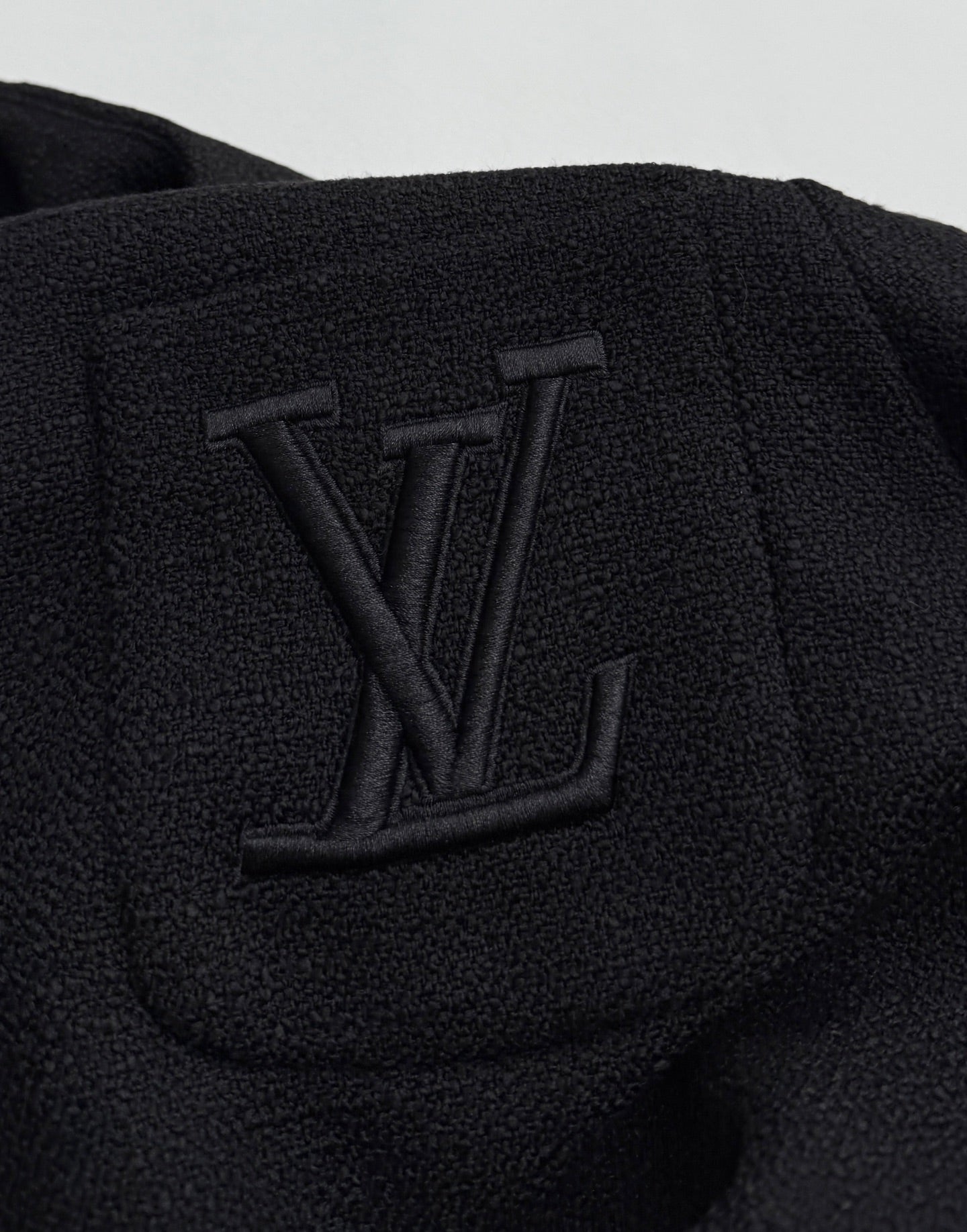 Black Louis Vuitton jacket chest detail with embossed LV monogram