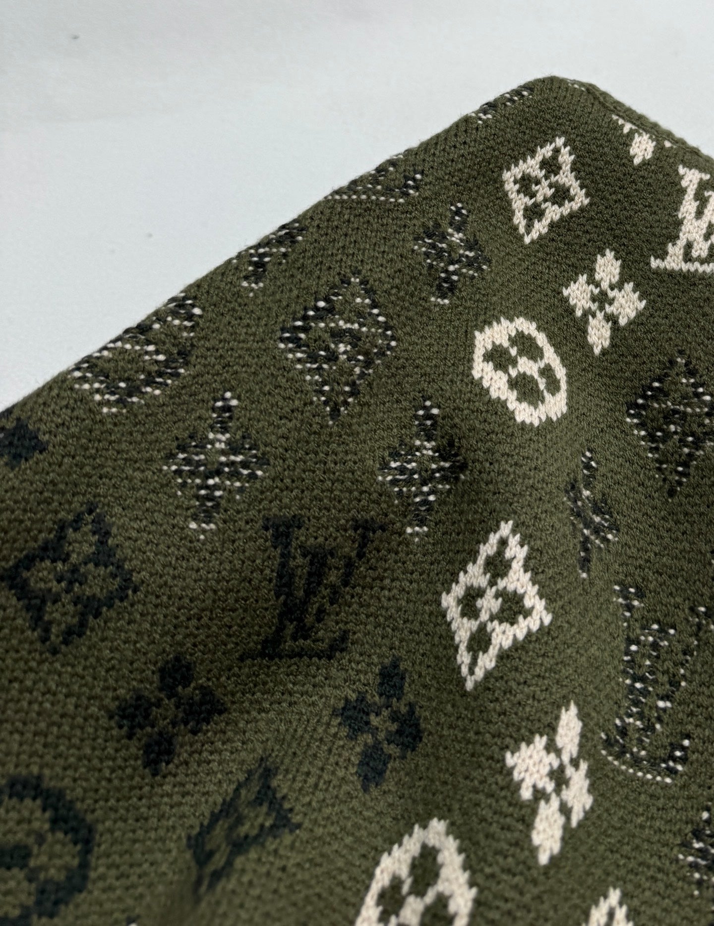 Green knit sweater knit texture with white and blue monogram motifs