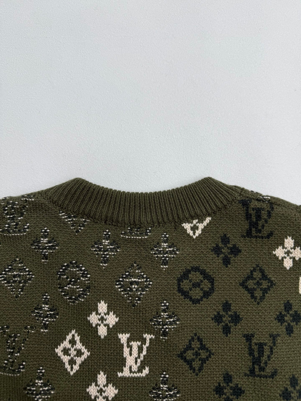 Green knit sweater upper back with monogram motifs and ribbed collar