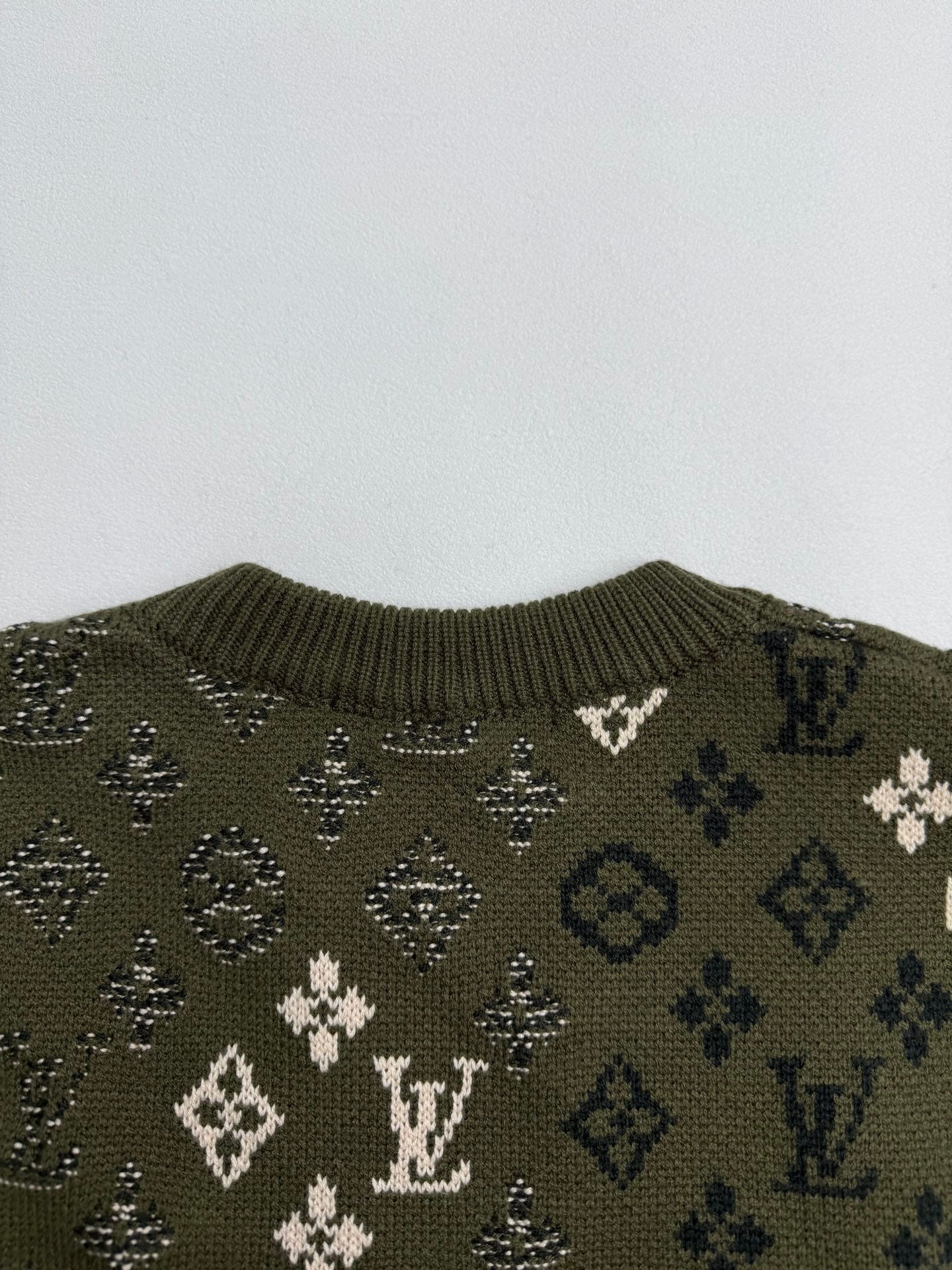 Green knit sweater upper back with monogram motifs and ribbed collar