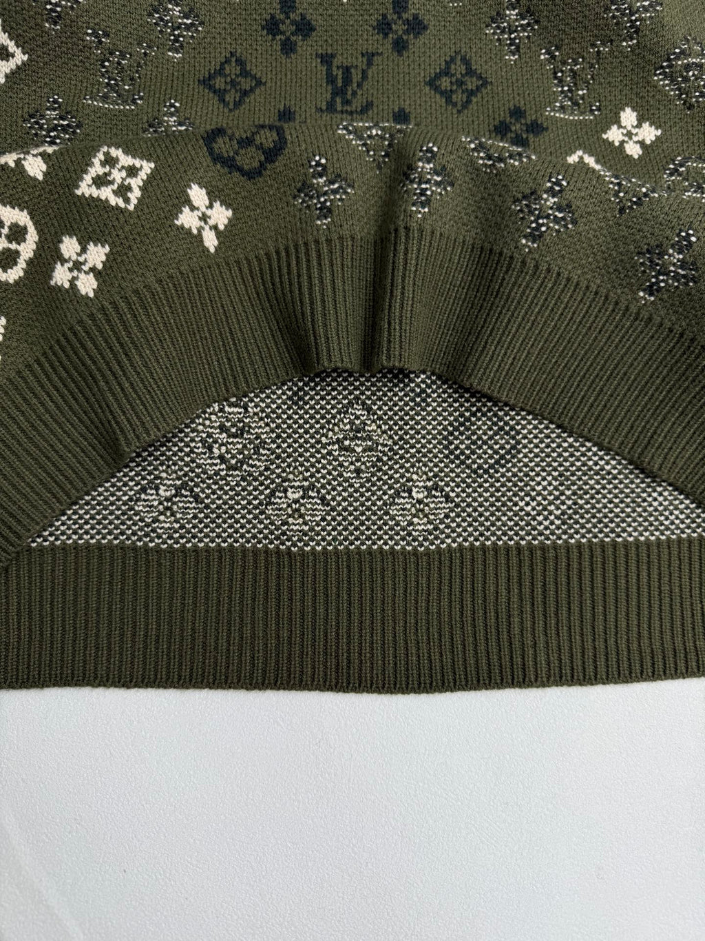 Green knit sweater hem with ribbed trim and monogram knit yoke