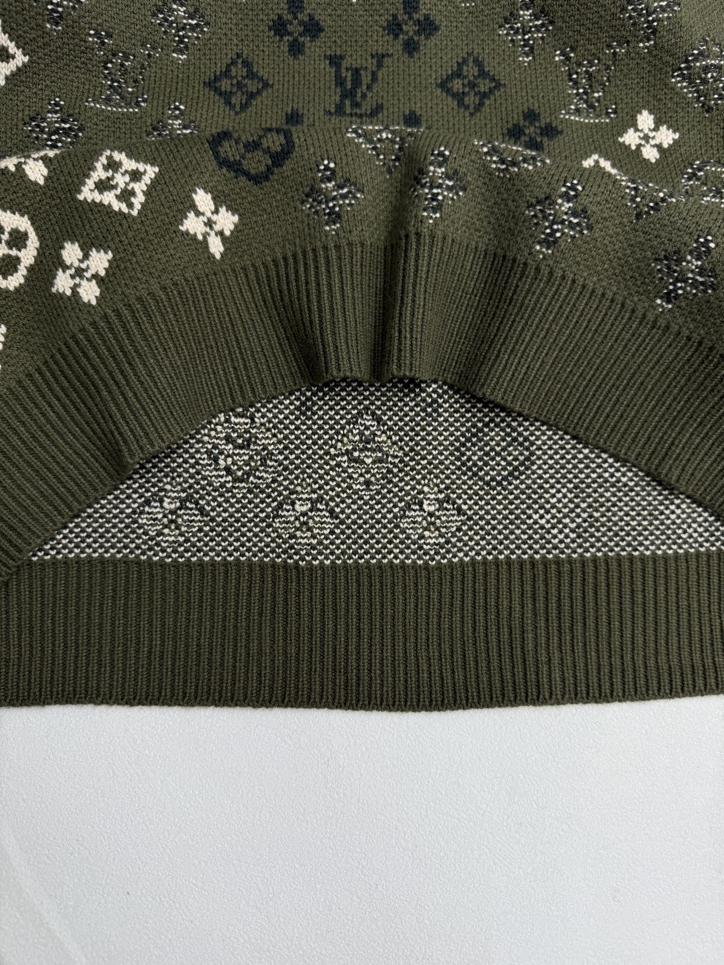 Green knit sweater hem with ribbed trim and monogram knit yoke