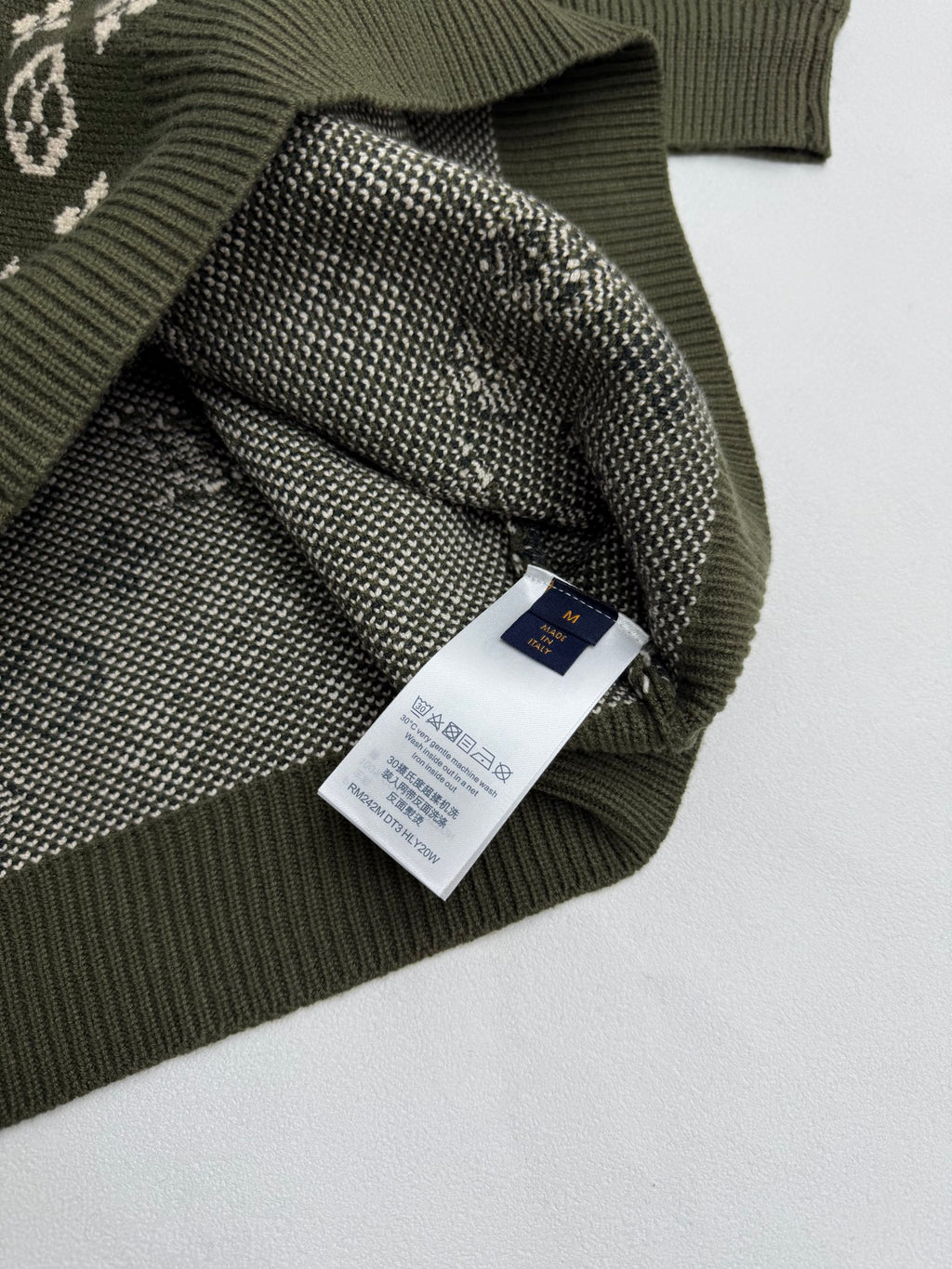 Green knit sweater with attached brand label and monogram knit cuff