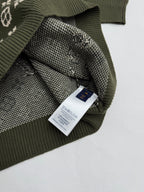 Green knit sweater with attached brand label and monogram knit cuff