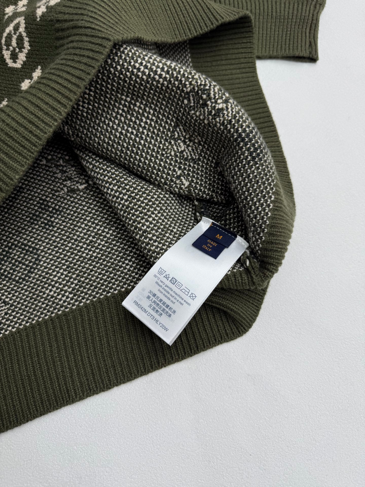 Green knit sweater with attached brand label and monogram knit cuff