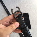 Black quilted leather belt with interlocking metal buckle and eyelets, held up