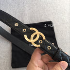 Black quilted belt strap with gold CC buckle and eyelets, angled close-up.