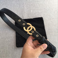 Black quilted belt with gold Chanel CC buckle, front close-up held in hand.