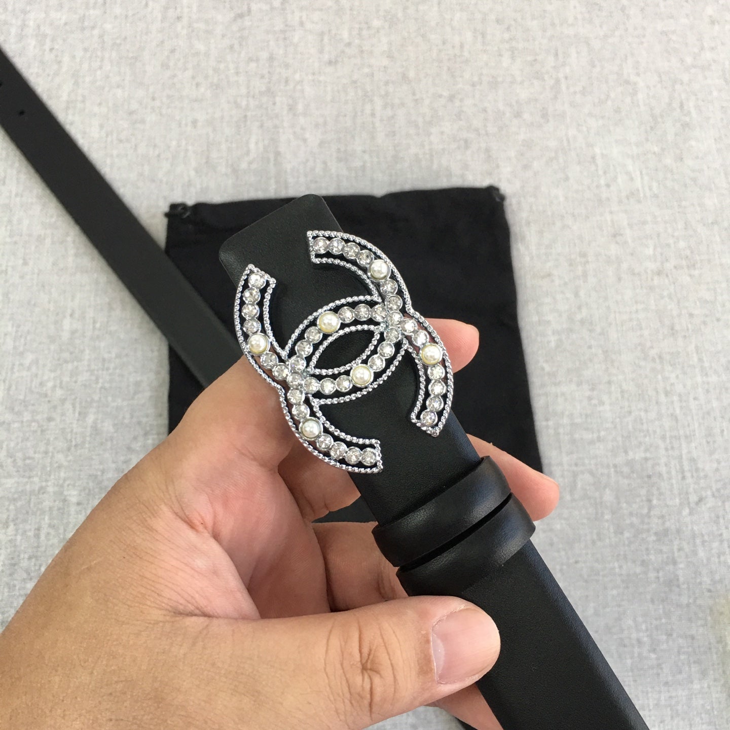 Chanel belt with rhinestone CC buckle detail on black strap, shown in close-up.