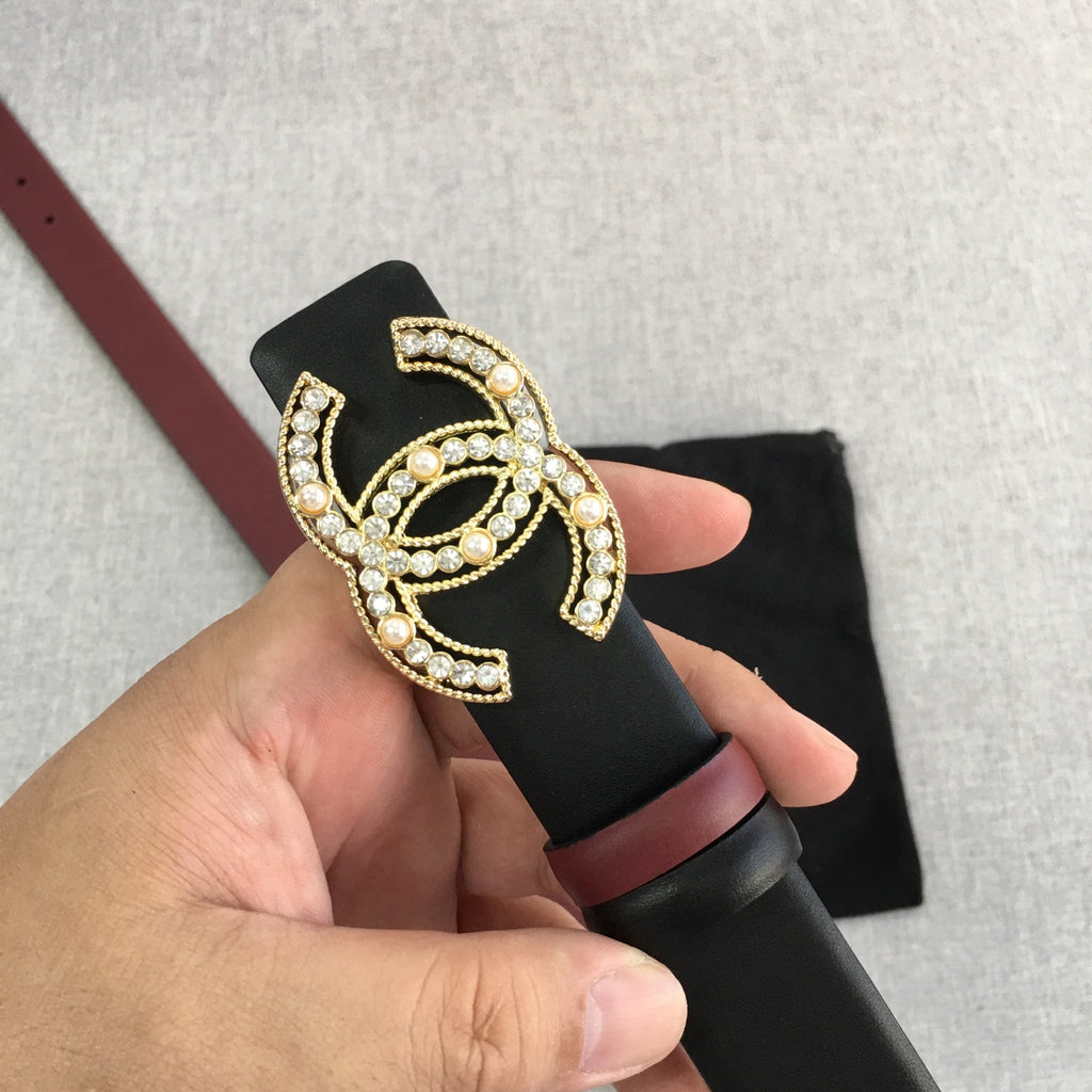 Chanel belt held up with black strap, burgundy edge, and gold jeweled CC logo