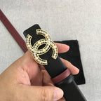 Chanel belt held up with black strap, burgundy edge, and gold jeweled CC logo