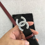 Black leather belt with burgundy edge and rhinestone CC logo buckle close-up