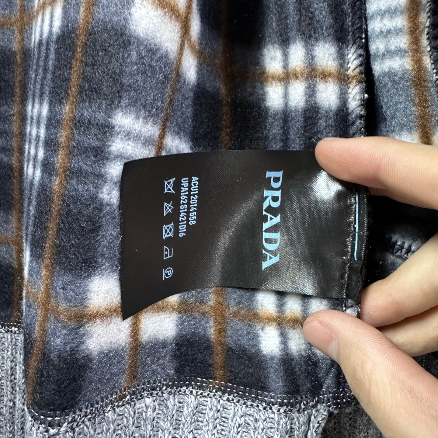 Plaid interior lining with PRADA care label on grey knit jacket