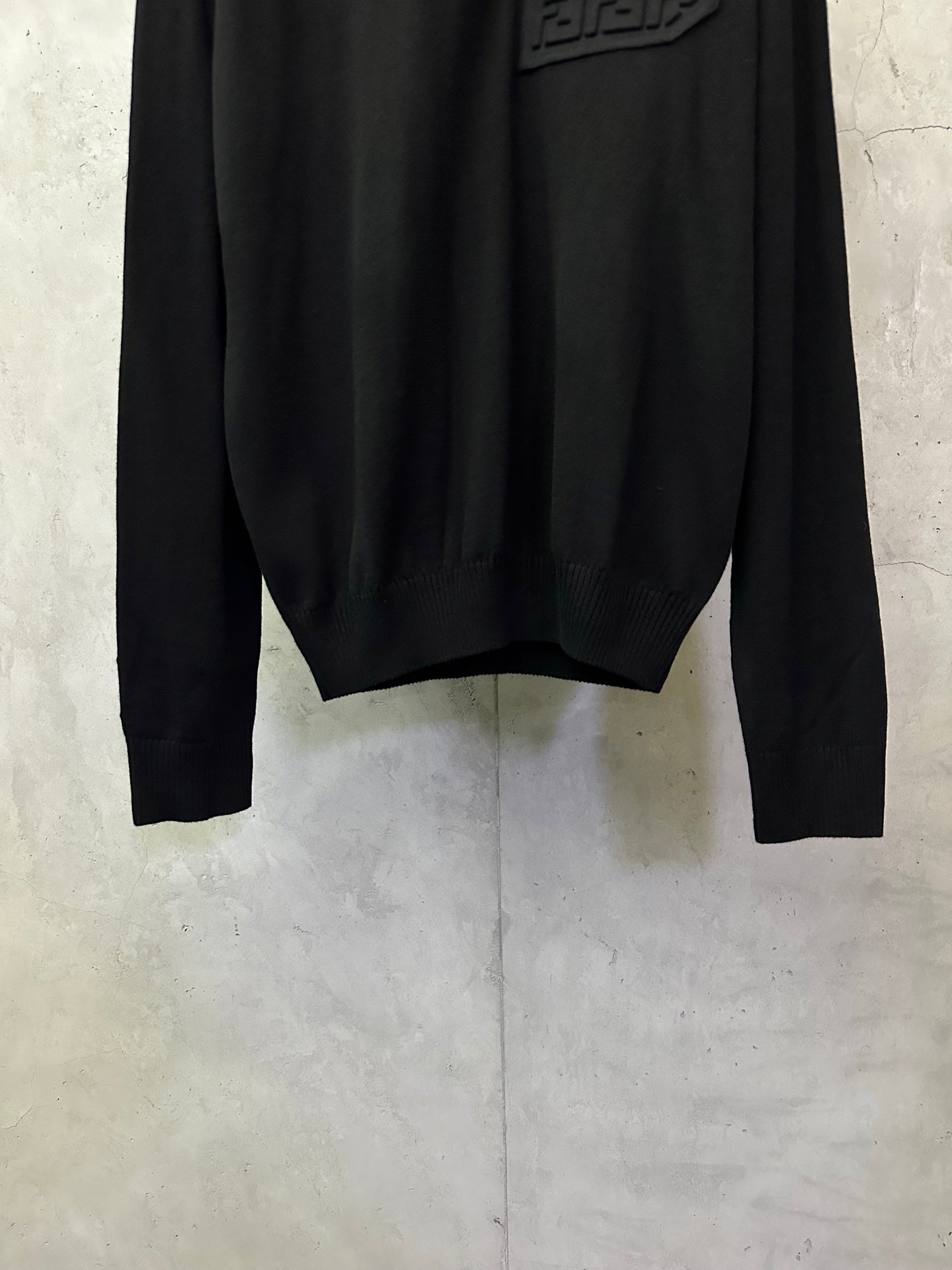 Black long-sleeve sweater hem and cuffs with ribbed knit detailing