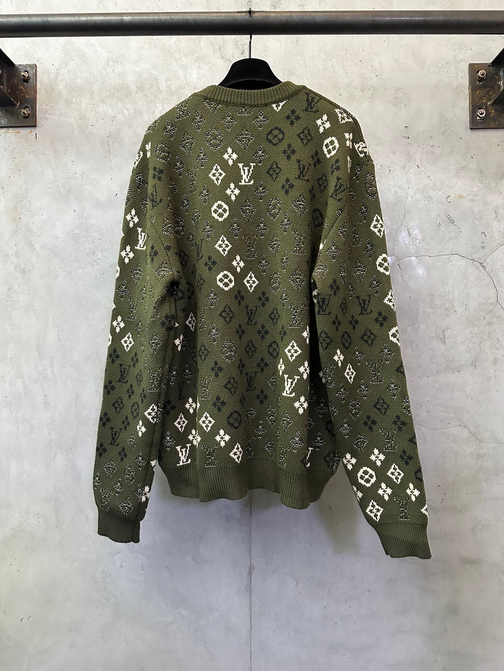 Long-sleeve knit sweater on hanger, olive green with allover white logo pattern
