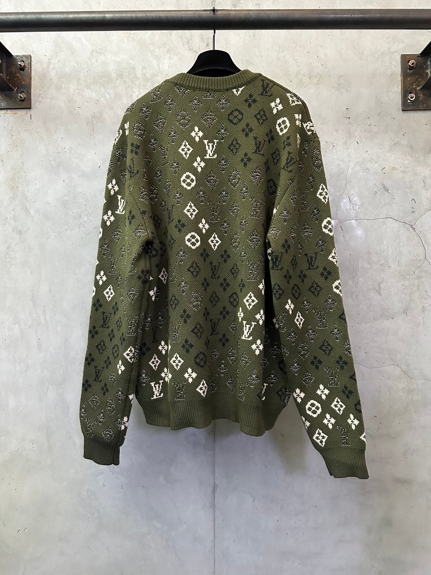 Long-sleeve knit sweater on hanger, olive green with allover white logo pattern