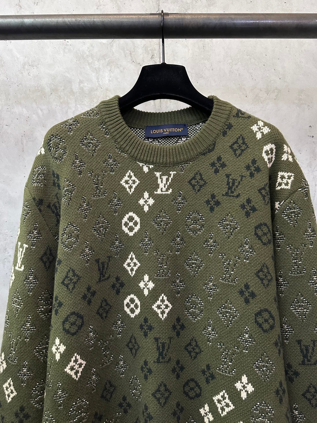 Long-sleeve sweater close-up, olive knit with white monogram motifs and crew neckline