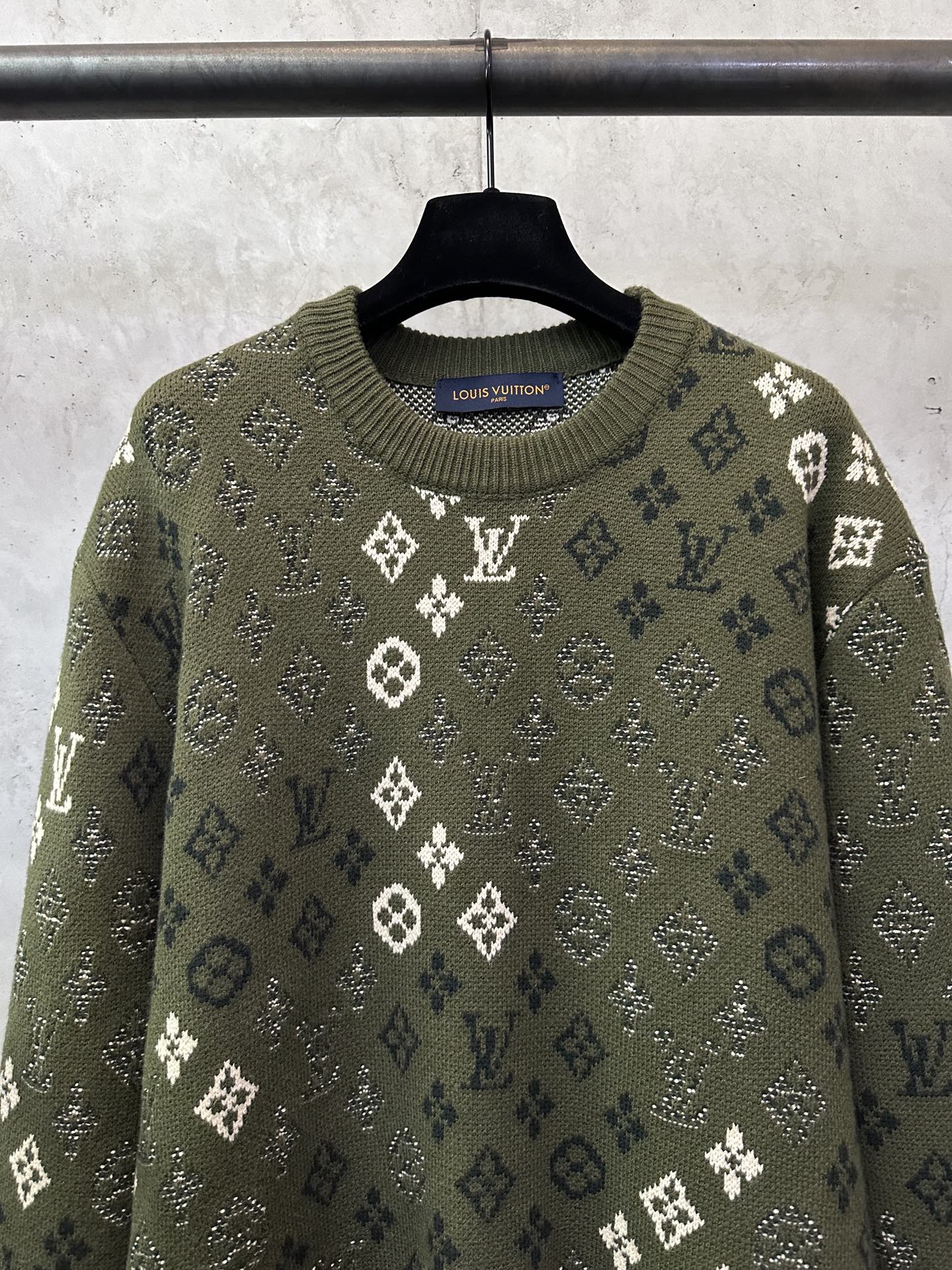Long-sleeve sweater close-up, olive knit with white monogram motifs and crew neckline