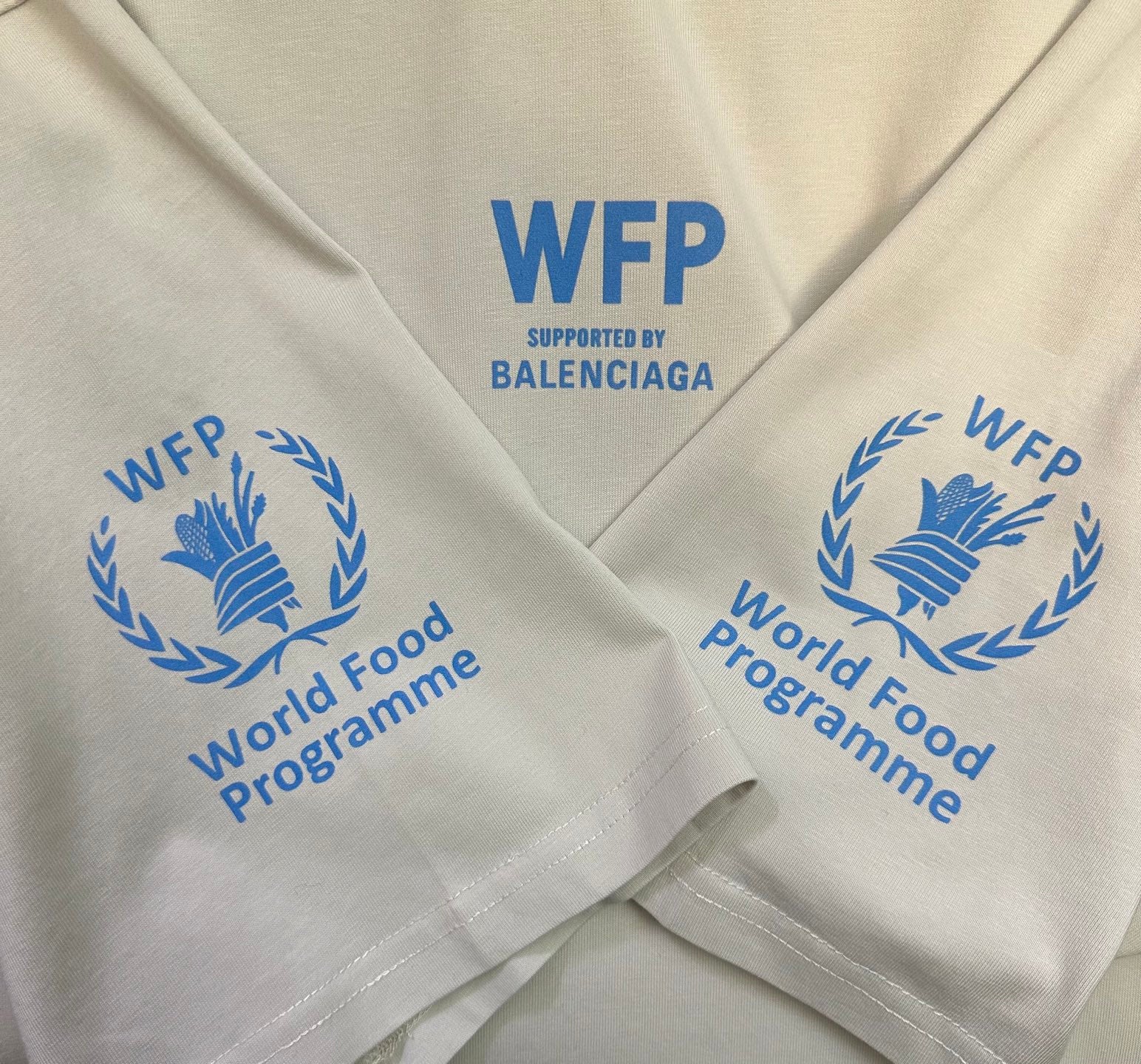 Off-white T-shirt close-up of blue WFP World Food Programme graphics on sleeves