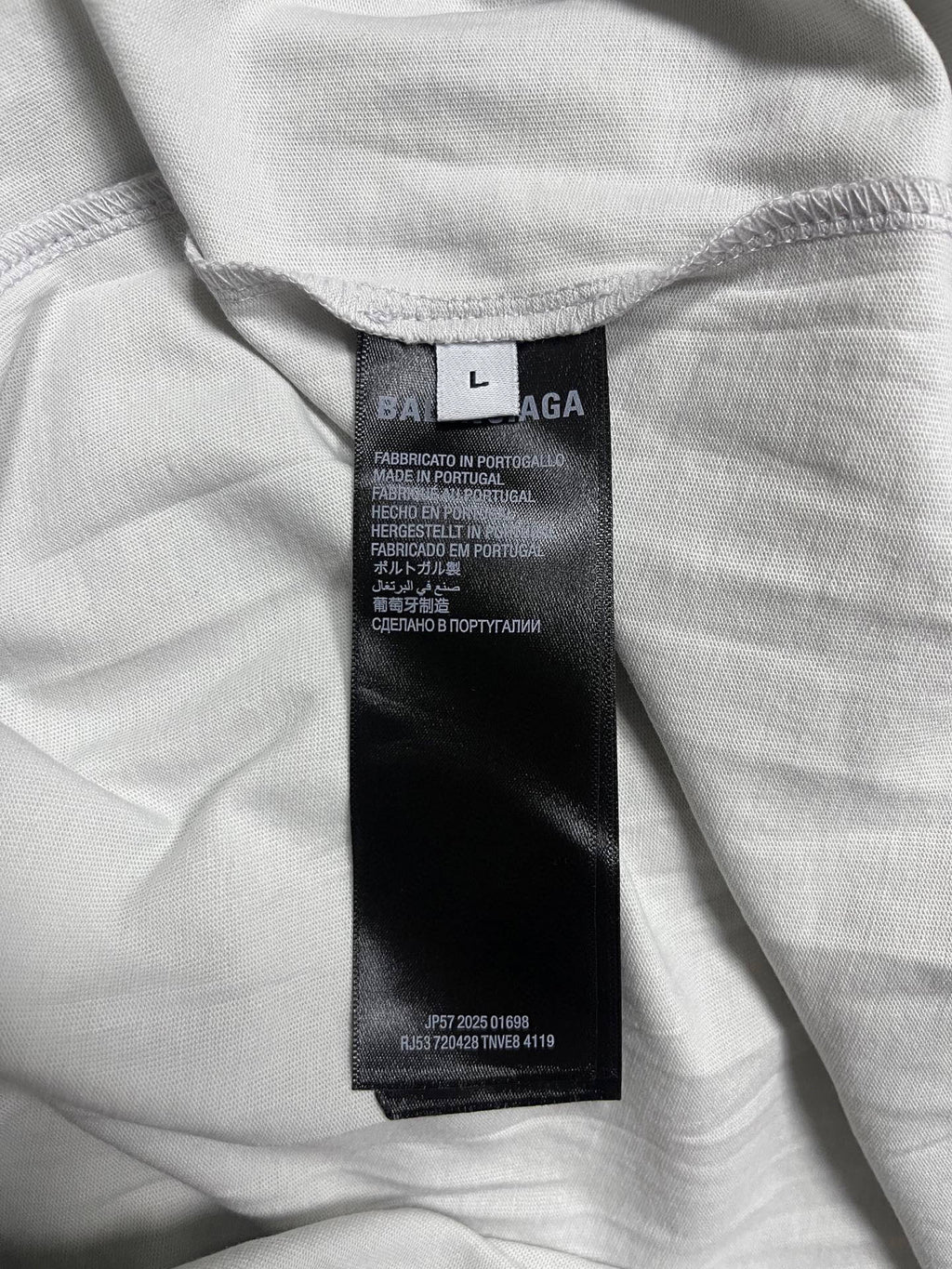 Off-white T-shirt with size/care label at inner neckline, folded fabric close-up