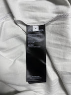 Off-white T-shirt with size/care label at inner neckline, folded fabric close-up