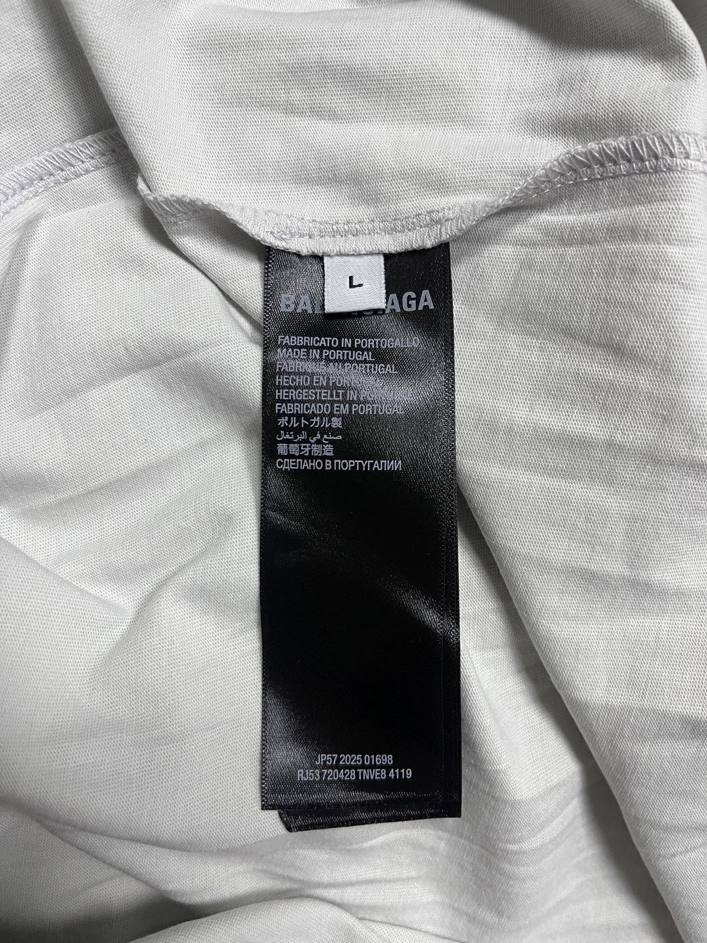Off-white T-shirt with size/care label at inner neckline, folded fabric close-up
