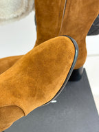 Tan suede boot with rounded toe and black-rimmed heel on display