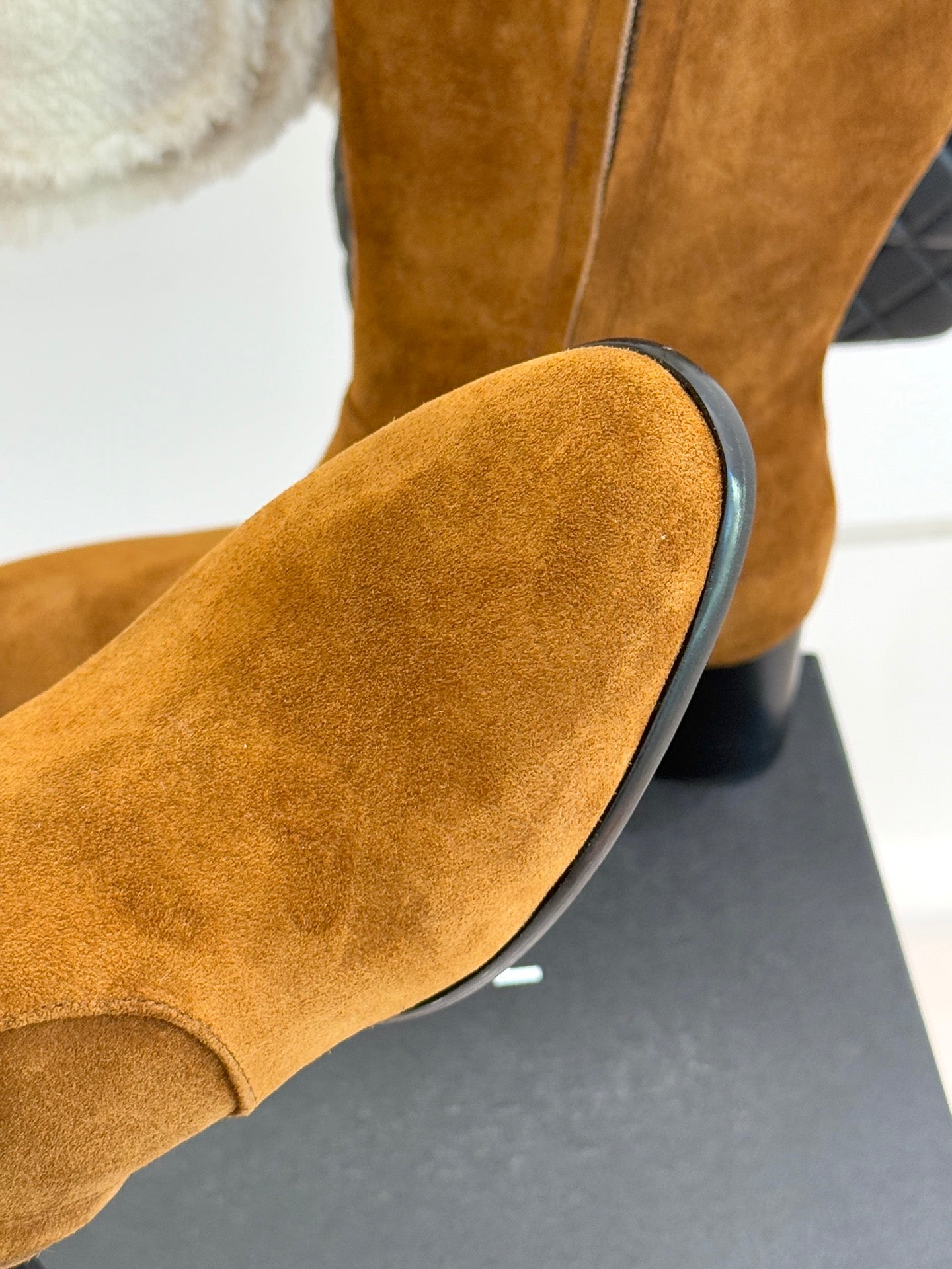 Tan suede boot with rounded toe and black-rimmed heel on display