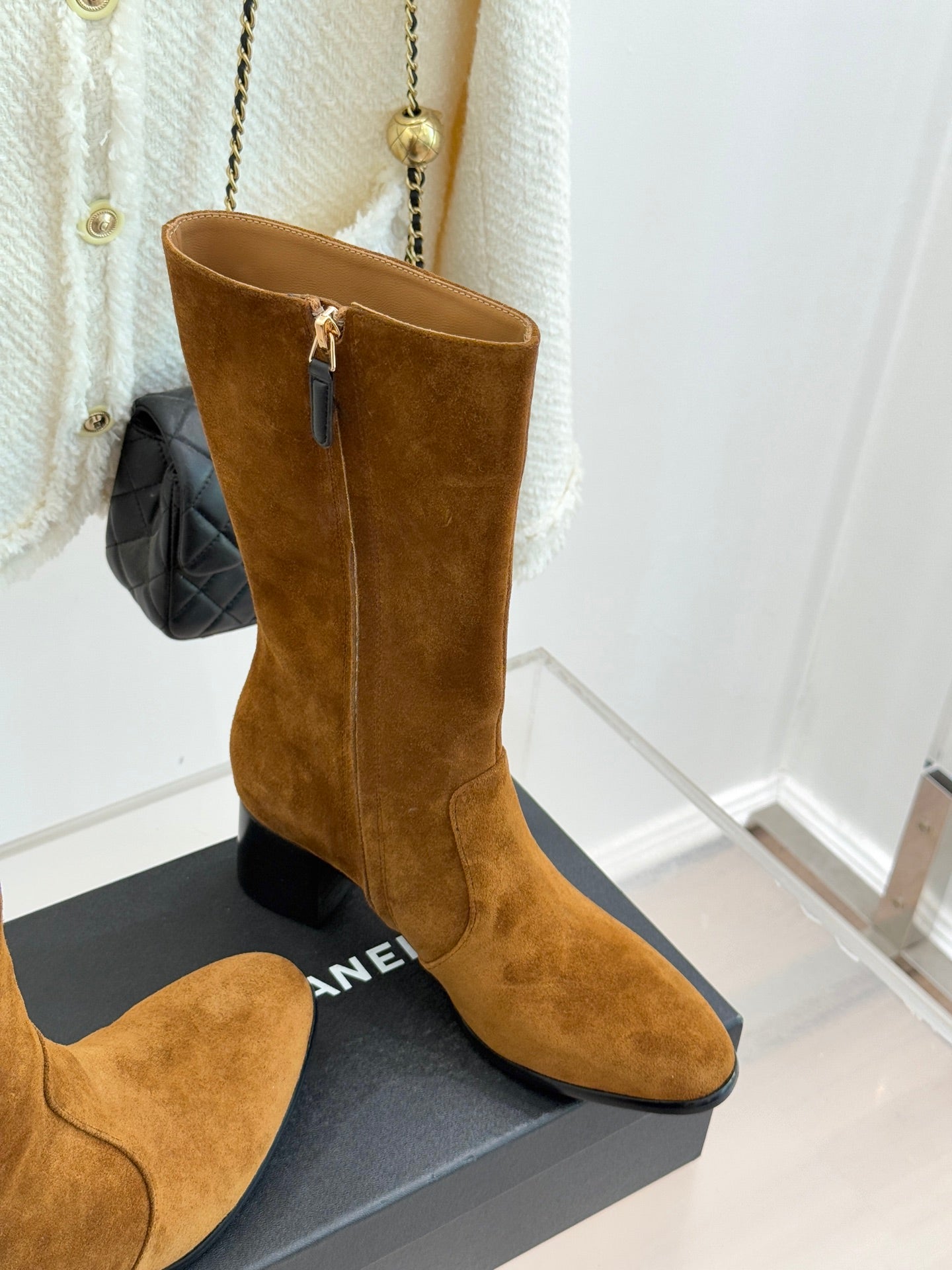 Tan suede tall heeled boots with front zipper and CC-style charm on side